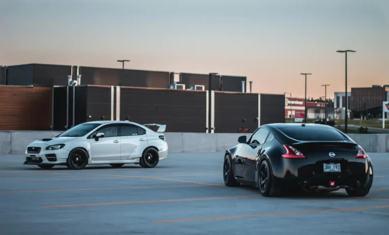 Duas carros esportivos BMW M2 em um estacionamento vazio ao entardecer, com prédio moderno ao fundo, destacando desempenho e estilo automotivo.