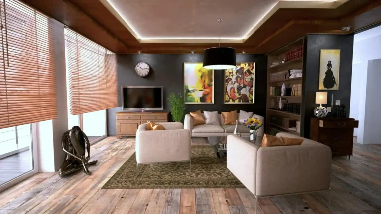 Sala de estar moderna com sofá bege, mesa de centro, televisão, livros nas prateleiras, quadros coloridos e iluminação aconchegante, perfeita para convivência e lazer.